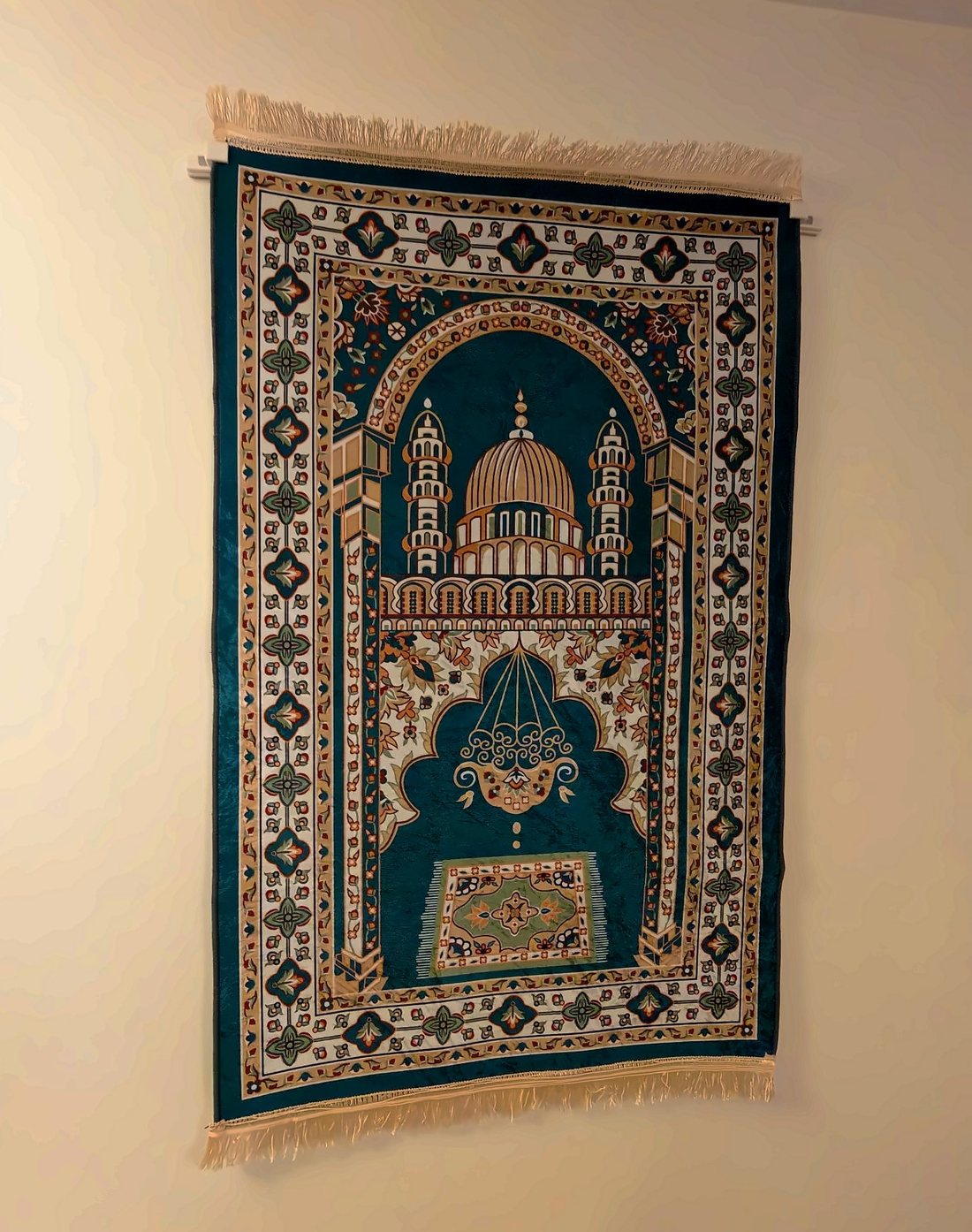 The same prayer mat seen from the side, hanging flat against the wall